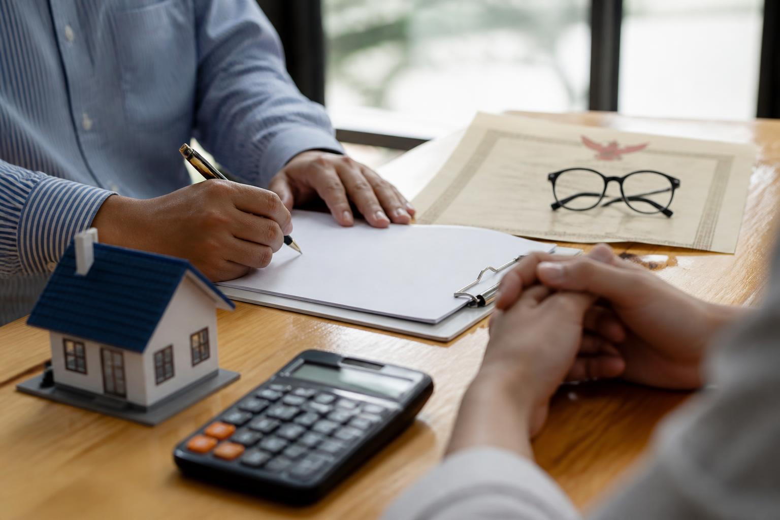 Signing a property sale agreement with title documents and a cost calculation on the desk